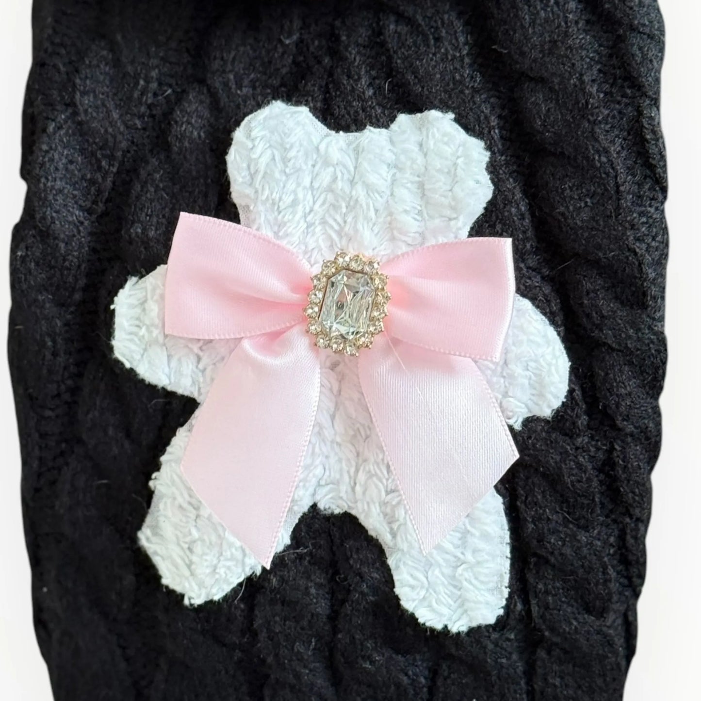 White lace dog coat with a pink bow and decorative brooch on a dark background