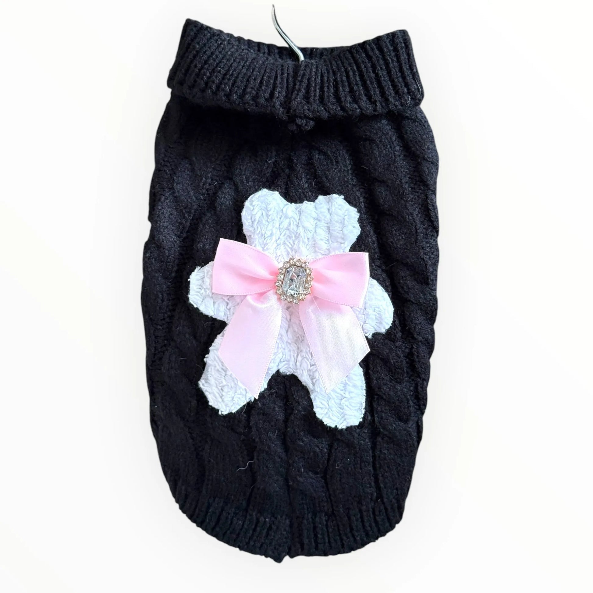 Black knitted dog sweater with a pink bow and white lace detail on a white background