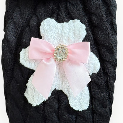 White lace dog coat with a pink bow and decorative brooch on a dark background