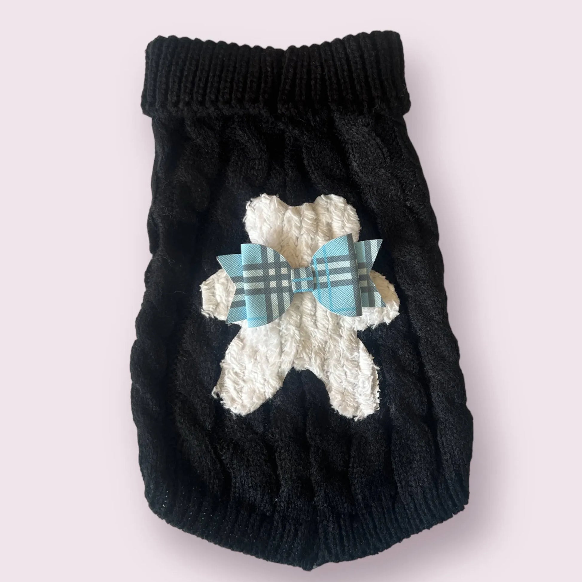 Black knitted dog sweater with white bear design and blue plaid bow on a light gray background
