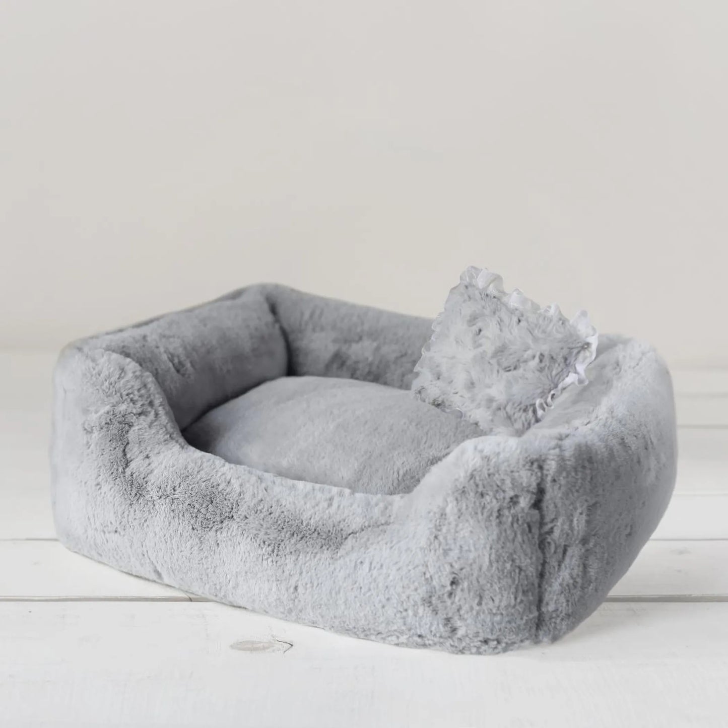Gray pet bed with a soft texture on a light wooden floor.
