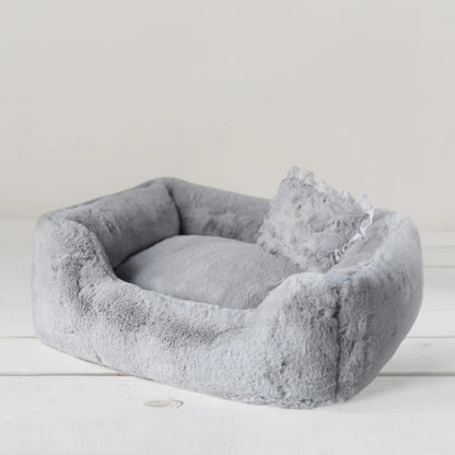 Gray pet bed with a soft texture on a light wooden floor.