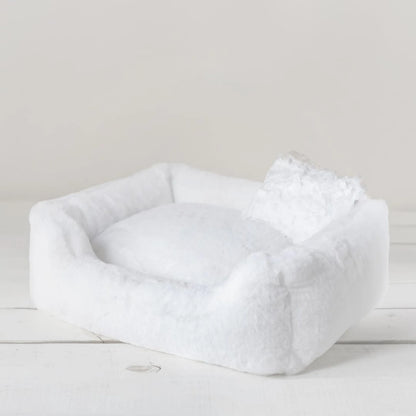 White pet bed on a light wooden floor with a neutral background