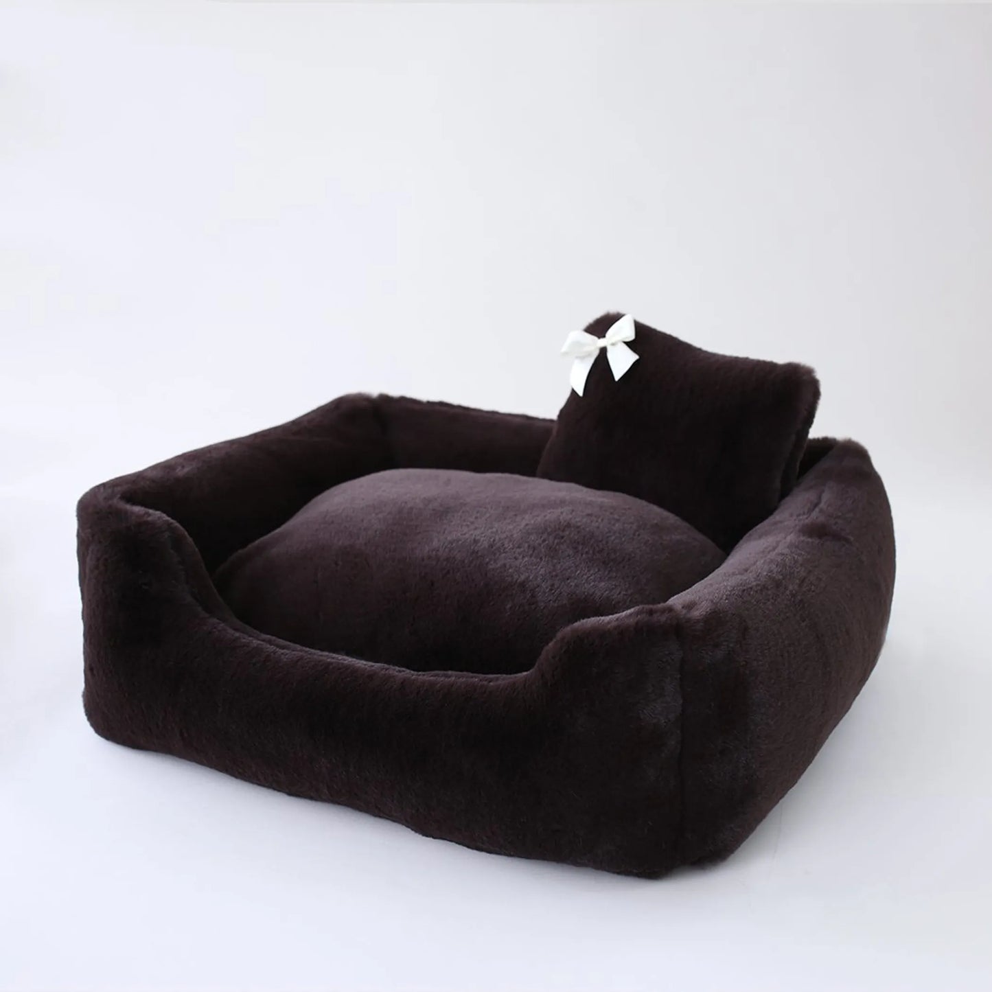 Brown pet bed with a white bow on a white background