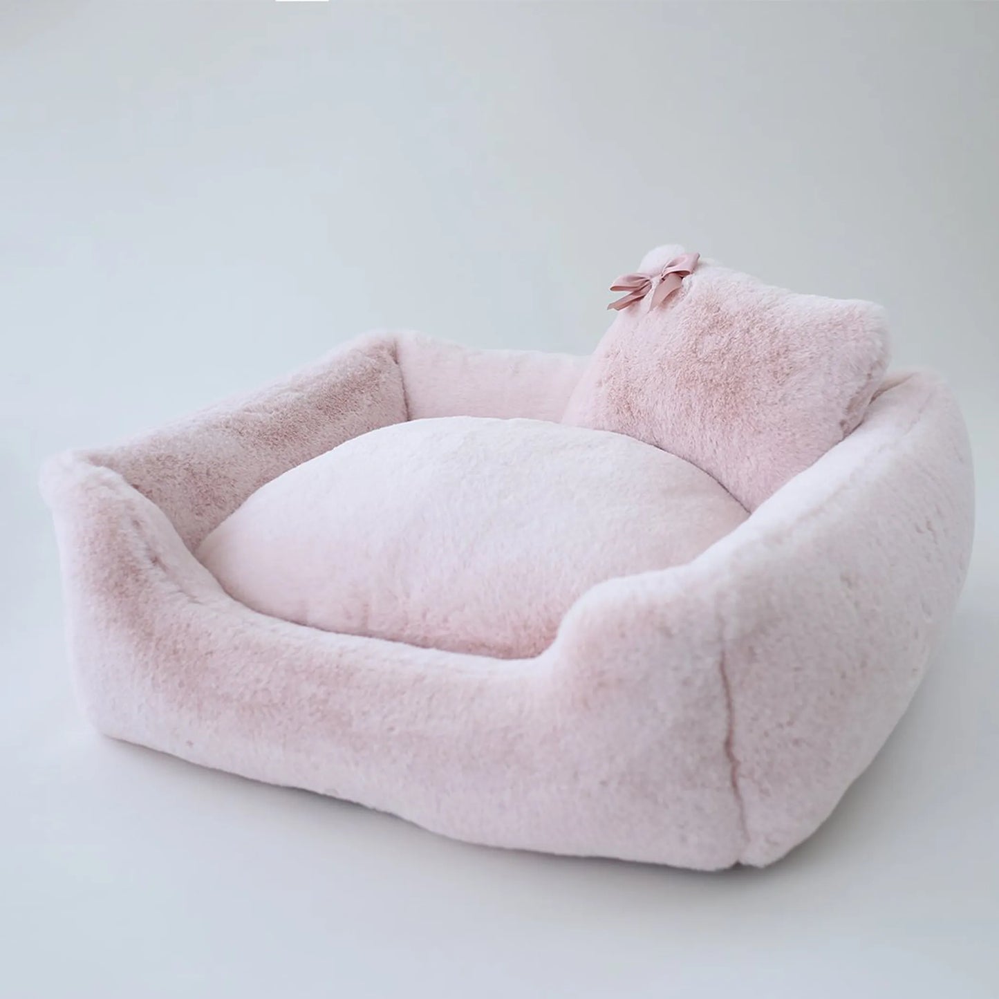 Pink pet bed with a pillow on a light gray background